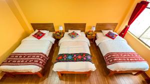 库斯科Andean Atoq Hostel的黄色墙壁的房间里设有三张床
