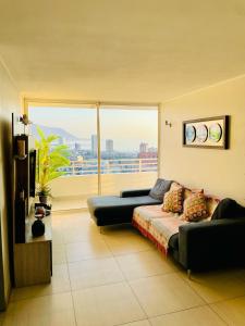 伊基克Departamento con espectacular Ubicación, Vista al Mar y Panorámica a todo Iquique的带沙发和大窗户的客厅
