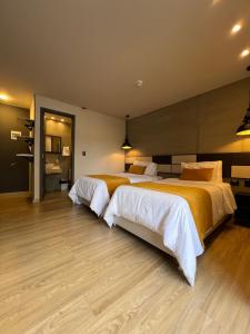 佩雷拉Balmoral Plaza Hotel的大客房铺有木地板,配有两张床。