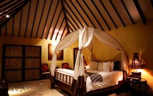 丹戎Hotel Tugu Lombok - CHSE Certified的一间卧室配有一张带天蓬的床