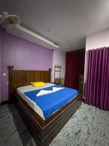 贡布The Vibe Guesthouse的一间卧室配有一张带蓝色床单和紫色墙壁的床。