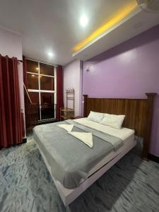 贡布The Vibe Guesthouse的一间卧室配有一张大床和紫色墙壁