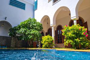 卡萨布兰卡Riad Tazi Casablanca的一座种植了树木和鲜花的建筑中的游泳池