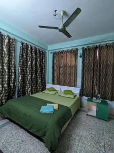 古瓦哈提Saikia Nest the Home-stay的一间卧室配有一张绿色的床和吊扇