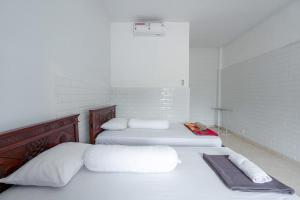 乌鲁瓦图SDK Homestay Uluwatu的白色客房的两张床,拥有白色的墙壁