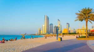 阿布扎比Furnished bedroom near Abu Dhabi Corniche的一片海滩,上面有人,后面有城市