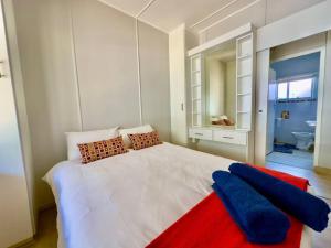 莫塞尔湾The Perfect Hartenbos Holiday Home的一间卧室配有白色的床和红色和蓝色枕头