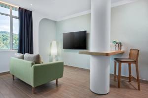 珍南海滩The Bayou Hotel Langkawi的客厅配有绿色椅子和电视