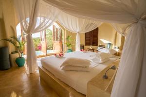 肯杜瓦桑给巴尔基林迪酒店的一间卧室配有一张带天蓬的白色床