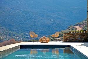 AchlaOnar Andros的一个带两把椅子和一张桌子的景观游泳池