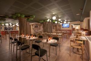夏蒙尼-勃朗峰Lykke Hotel Chamonix - ex Mercure的树木繁茂的房间里,餐厅里摆放着桌椅