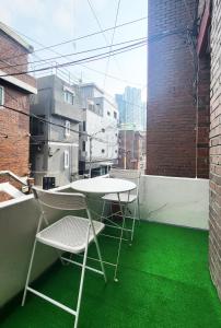 首尔New Corestay # Edae Stn 2min 2R 2F # near Hongdae的绿地阳台配有两把椅子和一张桌子