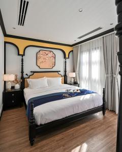 Bạc LiêuThiên Ân Boutique Hotel的一间卧室配有一张大床,床头板为蓝色和黄色