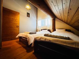 由布市Yufuin Log House no Yado Tom Sawyer的一间卧室设有两张床和木制天花板
