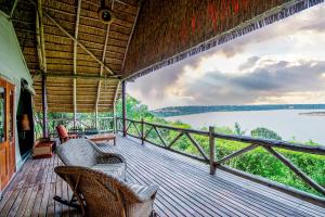 Katwe威亚野生山林小屋的一个带椅子的门廊,享有水景