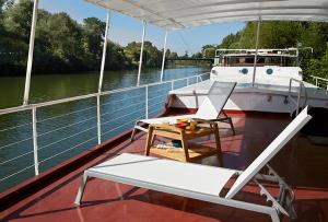 瓦兹河畔欧韦Péniche Daphné's的船上配有桌子和椅子