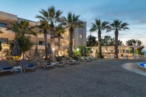 古瓦伊Gouves Bay by Omilos Hotels的前面有椅子和棕榈树的酒店