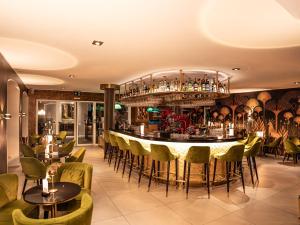 戈特利本Hotel Porto Sofie Gottlieben的餐厅设有酒吧,配有绿色的桌椅