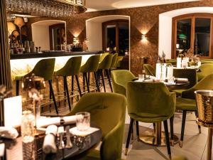 戈特利本Hotel Porto Sofie Gottlieben的一间设有绿色椅子的餐厅和一间酒吧