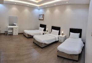 塔伊夫منتجع الكناري للفلل الفندقية الفاخرة Canary resort的配有白色墙壁和木地板的客房内的三张床