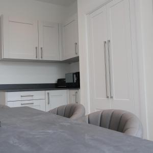圣奥尔本斯Alban Suites的厨房配有白色橱柜和桌椅