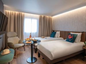 尼斯诺富特尼斯阿里纳斯阿罗伯特酒店的酒店客房设有两张床和一张桌子。