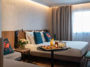 尼斯诺富特尼斯阿里纳斯阿罗伯特酒店的一间酒店客房,配有一张床铺,上面放着一个食物托盘