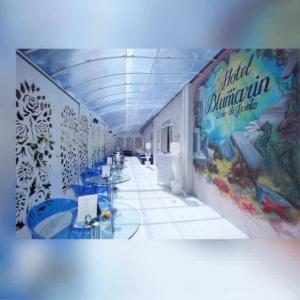 利多迪耶索罗HOTEL BLUMARIN的走廊上设有蓝色桌子和墙上的绘画
