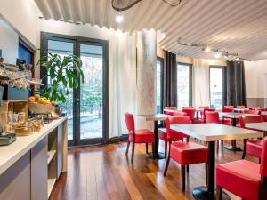 库尔布瓦拉德芳斯克莱贝尔爱达格公寓式酒店的餐厅设有红色的椅子和桌子以及窗户。