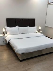 塔伊夫منتجع الكناري للفلل الفندقية الفاخرة Canary resort的一间卧室配有一张带白色床单和灯具的大床