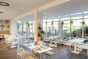 汉堡汉堡米特NH酒店的餐厅设有白色的桌椅和窗户。