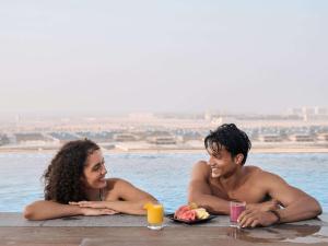 迪拜Aparthotel Adagio Dubai Deira的躺在游泳池里的男人和女人