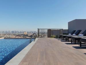 迪拜Aparthotel Adagio Dubai Deira的一个带椅子的屋顶游泳池,享有城市美景