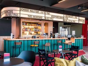 朗斯ibis Styles Lens Centre Gare的餐厅设有酒吧,配有桌椅