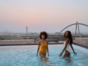 迪拜ibis Styles Dubai Deira的两个女人在一座建筑物顶部的游泳池里