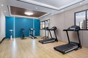 昆明昆明空港经济区戴斯精选温德姆酒店的健身房设有三台跑步机和一堵蓝色的墙壁