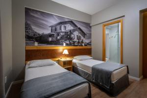 CaçadorBrivali Hotel e Eventos的一间设有两张床的房间和一幅房子的画
