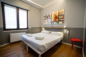 米兰Babila Hostel & Bistrot的卧室配有一张白色大床和红色椅子