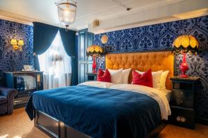 卑尔根Charmante - Skostredet Hôtel的一间卧室配有一张带蓝色墙壁和红色枕头的床