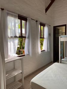 邦比尼亚斯Casa Mico Leão Dourado的卧室拥有白色的墙壁和窗户,配有一张床