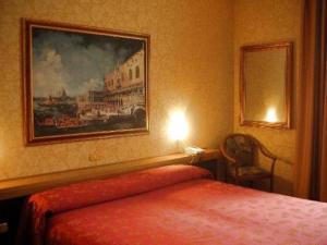普雷甘齐奥尔艾尔索雷酒店的卧室配有一张床,墙上挂有绘画作品