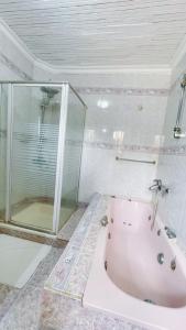 蒙巴萨Villa Ella的带浴缸和玻璃淋浴间的浴室。
