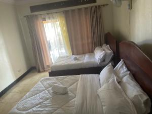 恩德培7 Days Hotel的一间卧室设有两张床和窗户。