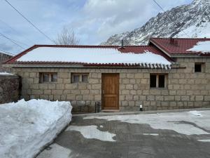 卡兹贝吉cozy apartments kazbegi的雪中带门的石头房子