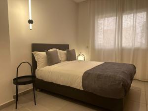 特马拉Residence Neya Harhoura的一间卧室设有一张床、一个窗口和一把椅子