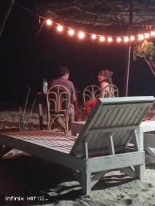 LocarocAkoya Beach Park and Cottages的男人和女人在晚上坐在野餐桌旁