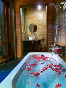 洛坤府Kung Nok Tha Resort Nakhon Si Thammarat的浴室设有装有红色鲜花的浴缸。