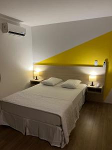 坎皮纳斯Mova Express Hotel - CAMPINAS的一间卧室设有一张黄色墙壁的大床