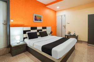 艾哈迈达巴德水晶酒店的一间卧室配有一张带橙色墙壁的大床