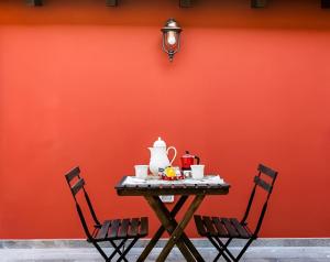 卢卡Cortile in centro - Charm Suite Heart of Lucca的一张桌子,上面有茶壶和两把椅子,靠在红色的墙上